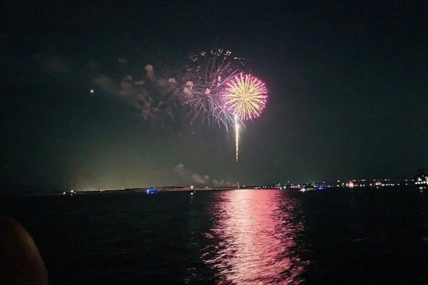 Escena nocturna con fuegos artificiales sobre el agua, que se reflejan en la superficie. 3