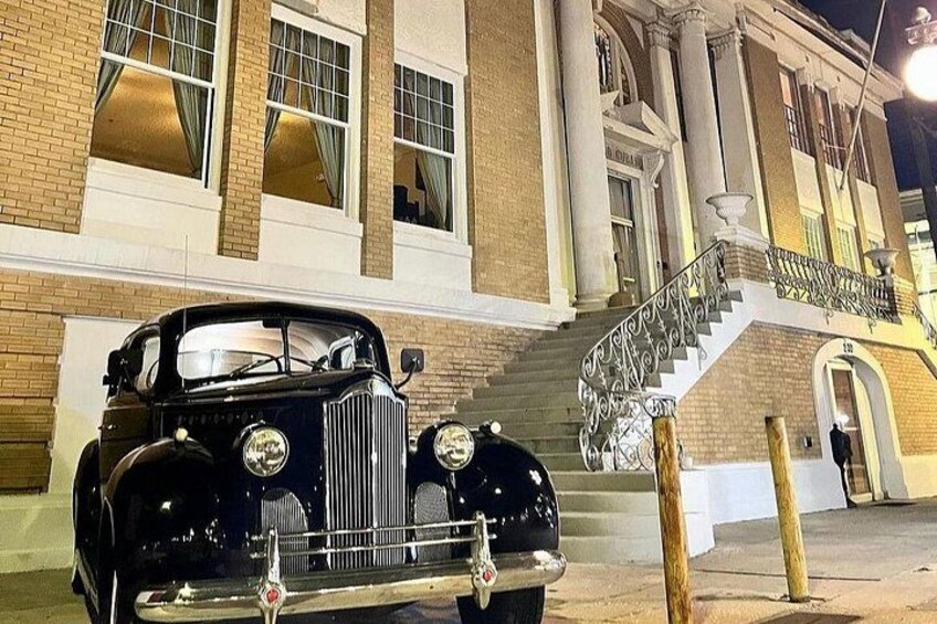 A vintage black car parked in front of a building with a grand staircase and columns. 2