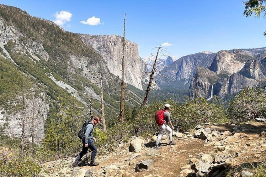 Two hikers on a rocky trail with a mountainous landscape in the background. 3