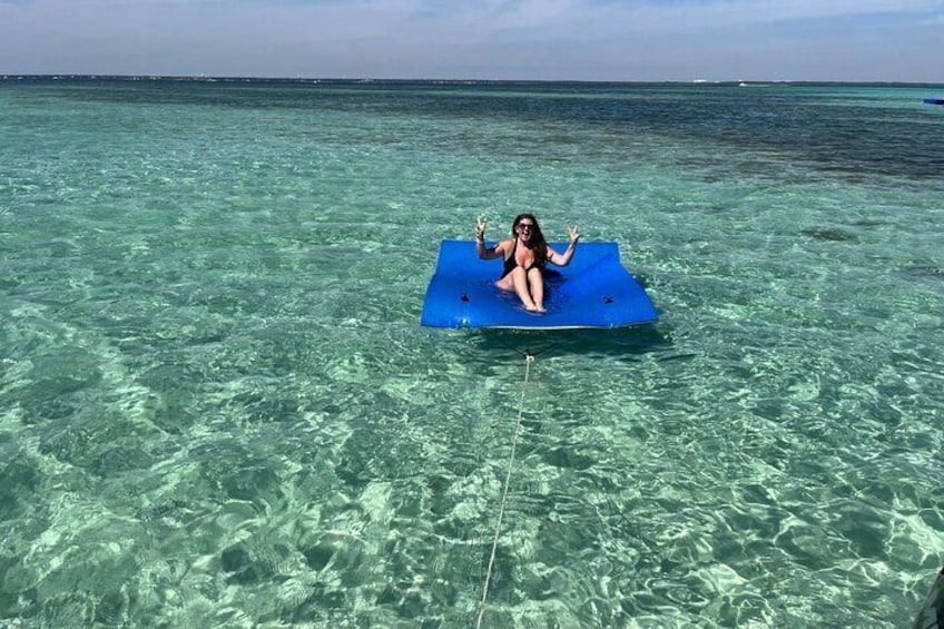 Iemand drijft op een blauwe luchtbed in helder ondiep water. 1