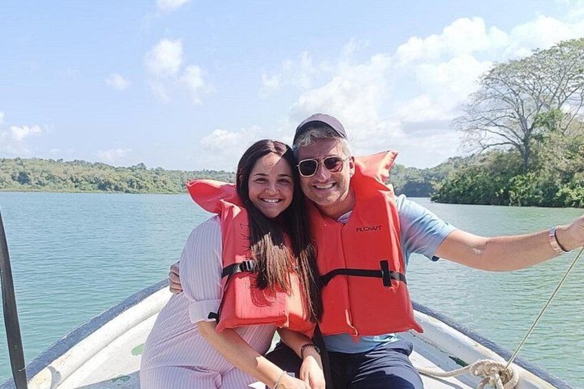 Two people on a boat wearing life jackets, with a calm lake and greenery in the background. 5