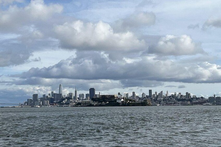 A city skyline across a body of water with clouds in the sky. 5