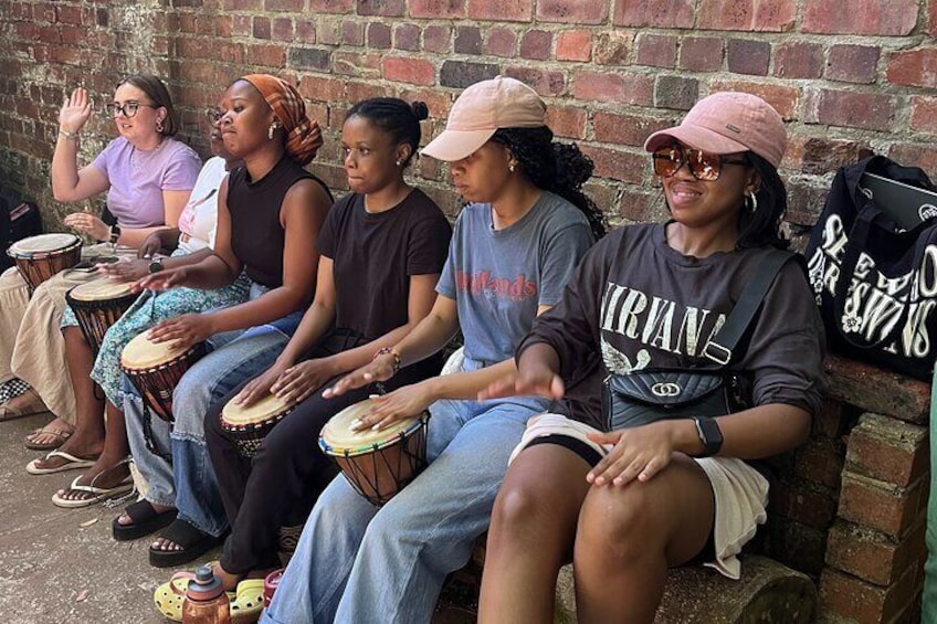 Un grupo de personas sentadas en un banco tocando la batería. 1
