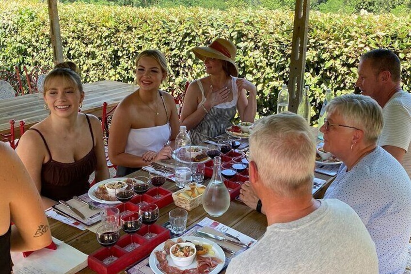 Un grupo de personas cenando al aire libre en una mesa con diversos platos y bebidas. 1