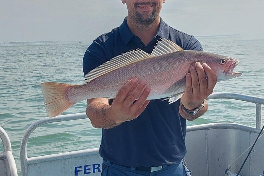 En person som håller i en fisk på en båt. 2