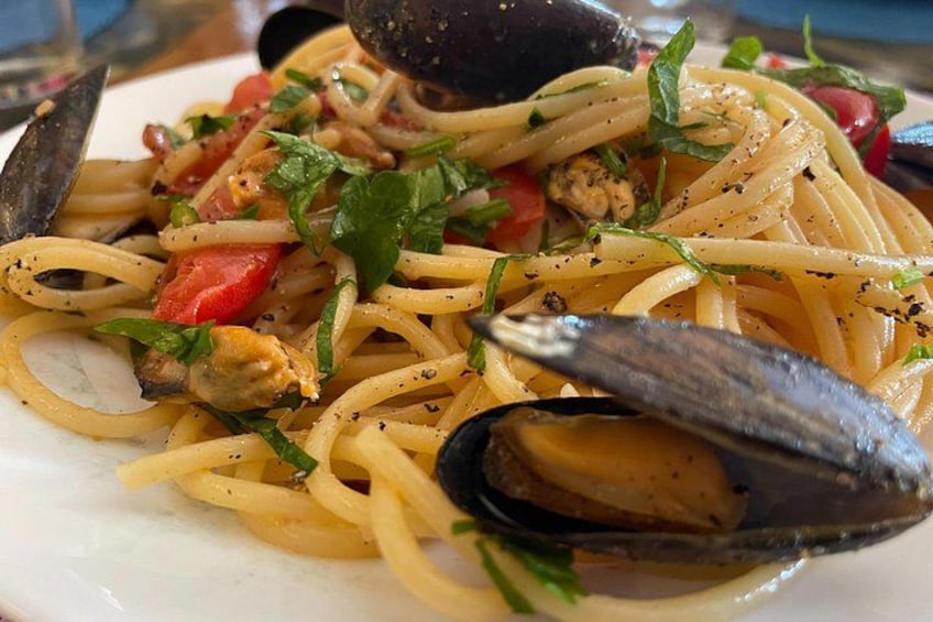 A plate of spaghetti with mussels, tomatoes, and herbs. 2