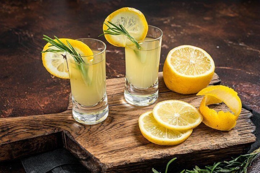 Deux verres d’une boisson à base de citron, garnis de tranches de citron et de romarin, posés sur une planche en bois. 3