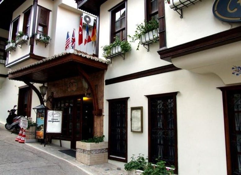 A building with multiple flags, a signboard, and potted plants. 5