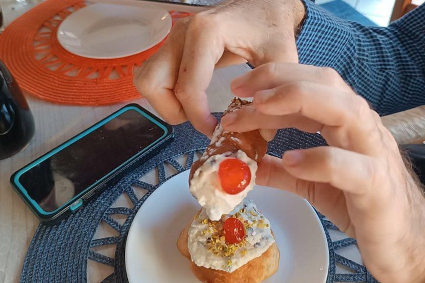 A person holding a pastry with a cherry on top. 2