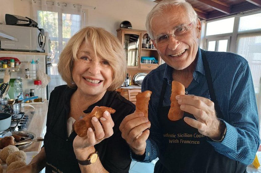 Two people holding bread in a kitchen. 1