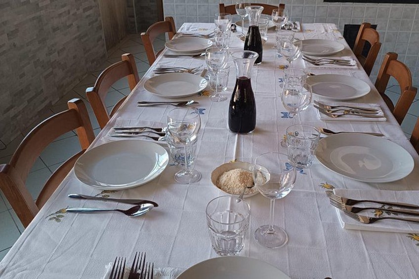 A dining table set with plates, cutlery, glasses, and a bottle. 4
