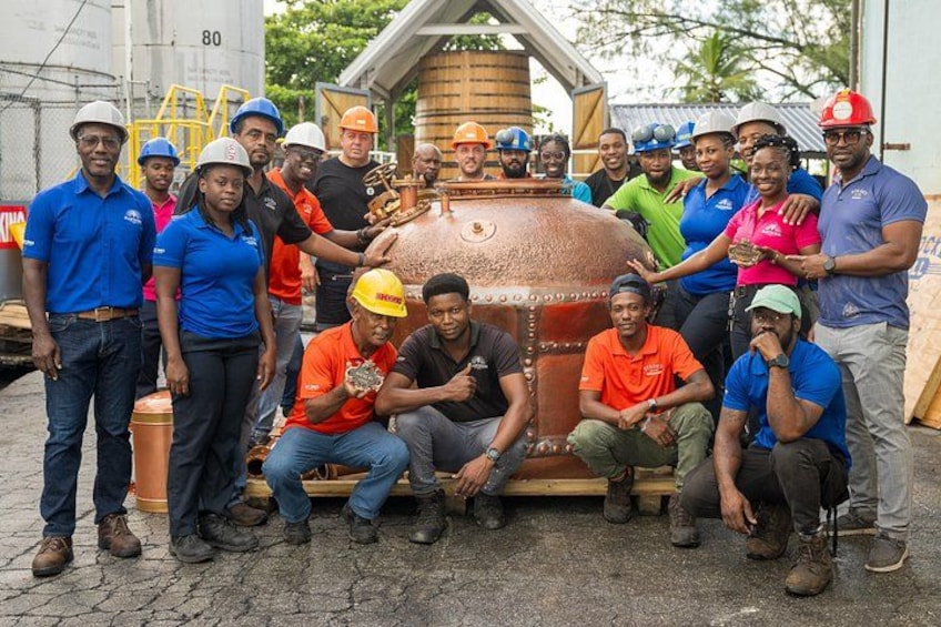 A group of people gathered around a large industrial tank, some wearing safety helmets. 3