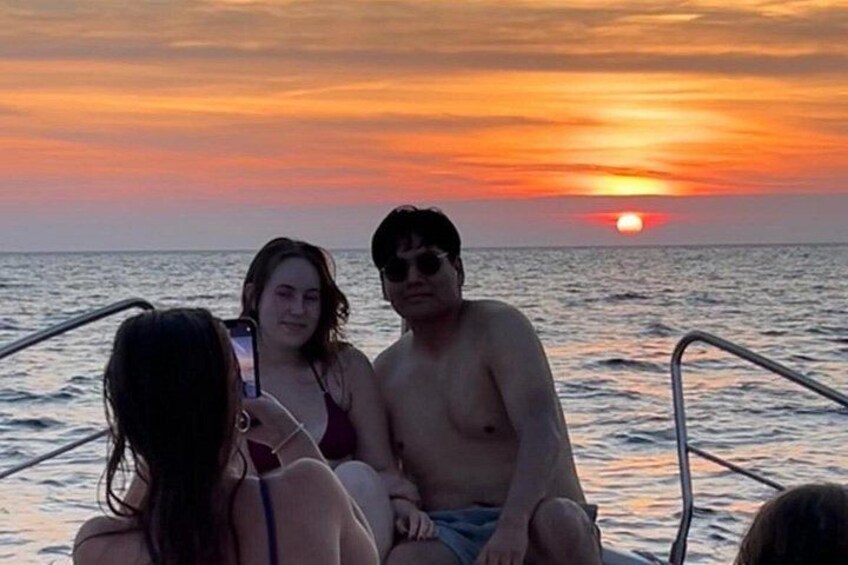 Ein Sonnenuntergang über dem Meer mit Menschen in einem Boot. 4