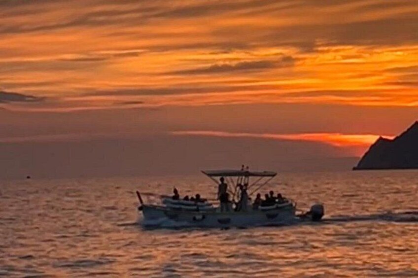 Ein Boot mit Personen auf dem Wasser bei Sonnenuntergang. 2