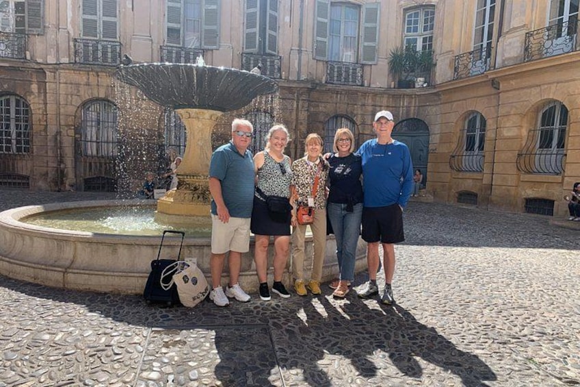 Un groupe de personnes se tient devant une fontaine, avec un bâtiment en arrière-plan. 2