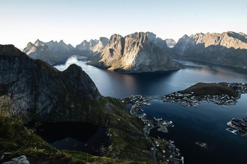 A mountainous landscape with a fjord, a small harbor, and a road leading into the mountains. 4