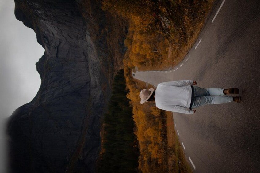 Eine Person steht auf einer Straße, im Hintergrund eine Berglandschaft. 3