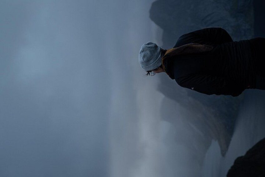 A person standing on a rocky surface with a misty background. 3