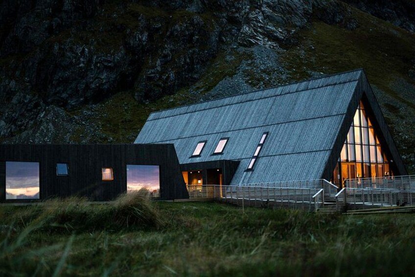A modern building with a sloped roof, large windows, and a staircase leading to the entrance. 3