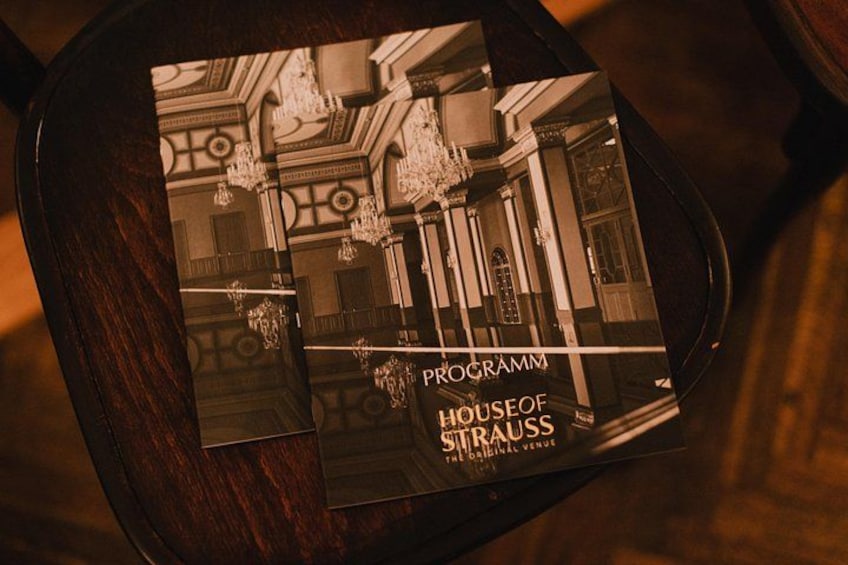 A brochure with a classical building interior, chandeliers, and ornate details. 2