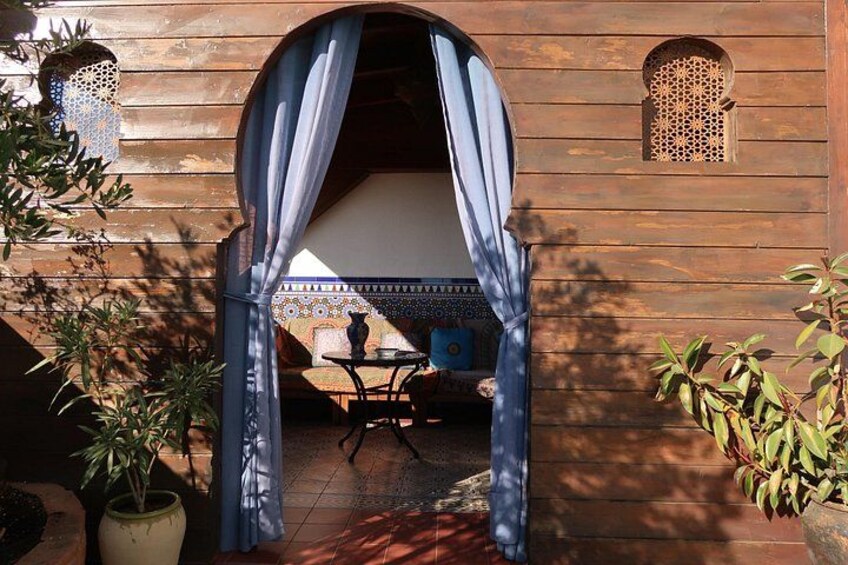 A wooden building with a covered entrance, potted plants, and a tiled patio. 4