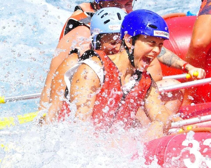 People in a raft with helmets, splashing water. 5