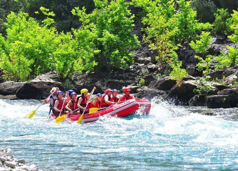 A group of people in a red raft navigating a river surrounded by rocks and greenery. 4