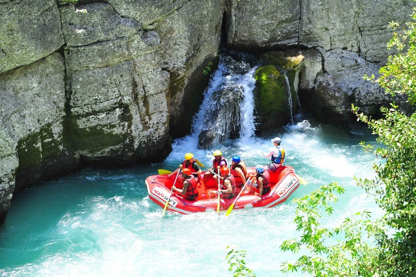 A group of people rafting down a river with a waterfall. 3