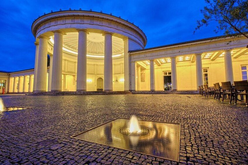 A classical building with columns and a fountain in the foreground. 3