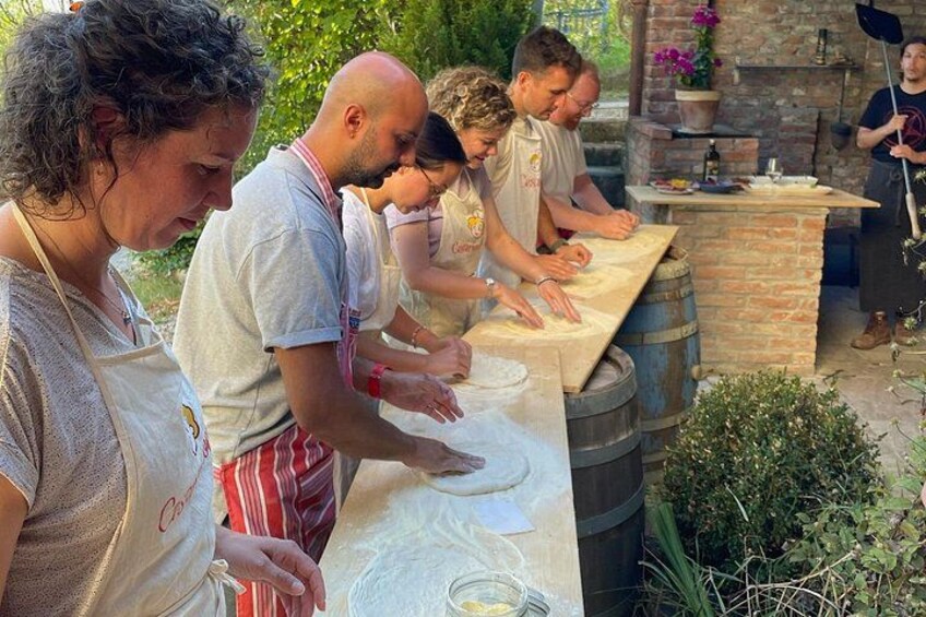People preparing food outdoors with a brick oven and barrels. 2