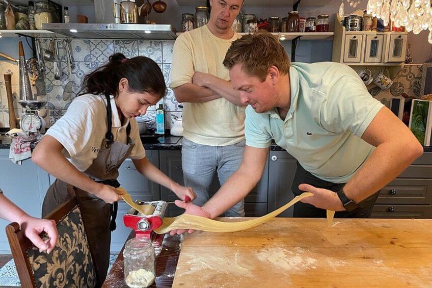 Three people in a kitchen preparing dough on a wooden table. 3