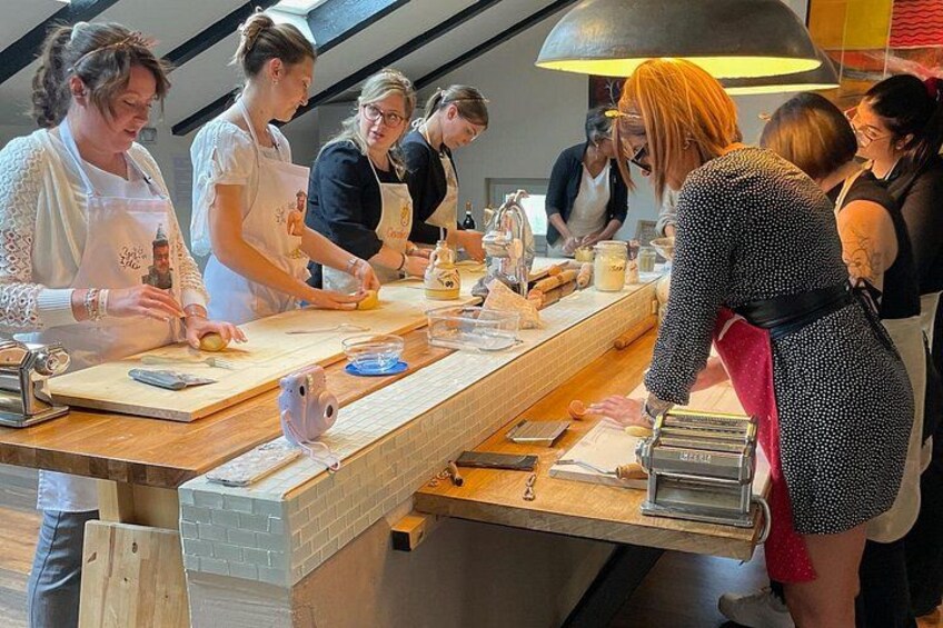 A group of people preparing food at a long wooden counter with various kitchen tools and ingredients. 5