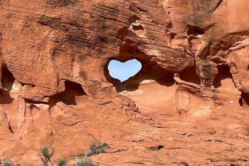 A red rock formation with a heart-shaped opening. 1