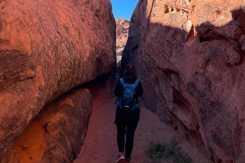 A person hiking through a narrow canyon with red rock walls. 3
