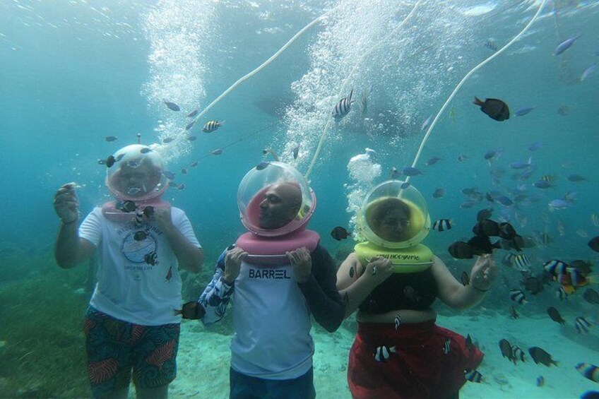 Drei Personen mit Schnorcheln unter Wasser, umgeben von Fischen. 4