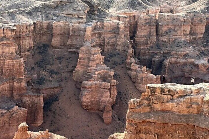Un canyon aux formations rocheuses en strates, avec une personne debout sur une corniche. 5