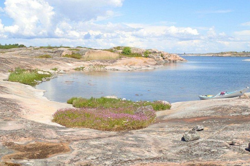 A calm river, rocky shore, and a canoe. 2