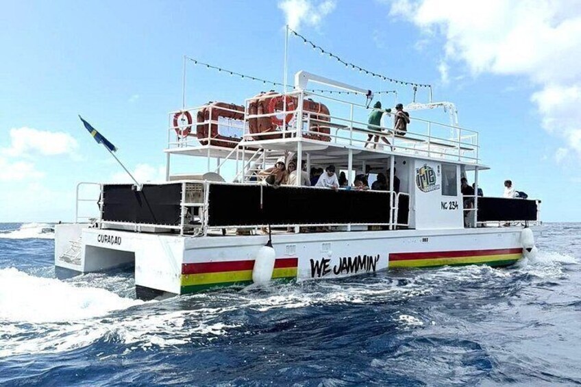 A boat named 'We Jammin'' with people on board, moving through the ocean. 2