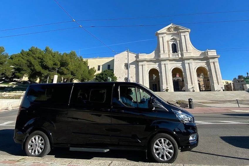 A black van parked in front of a white building with a clock tower. 5