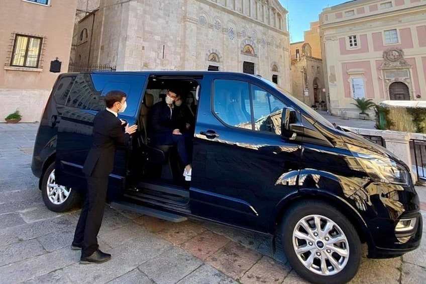 A black van parked on a cobblestone street with a building in the background. 3