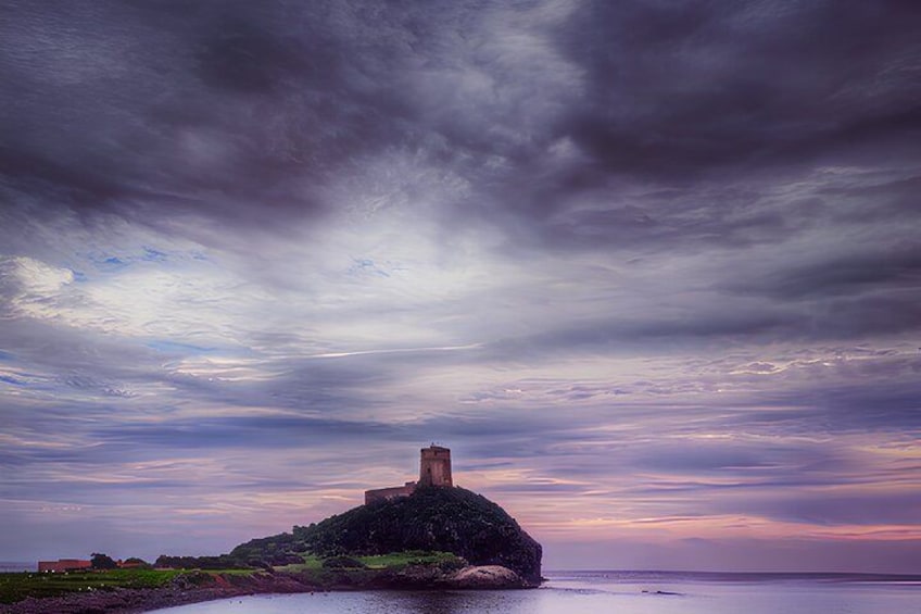 A coastal landscape with a prominent tower on a rocky outcrop, surrounded by a dramatic sky. 2