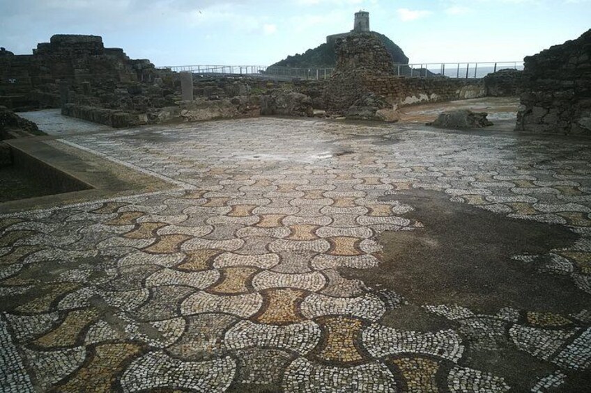 An ancient mosaic floor with stone structures in the background. 2