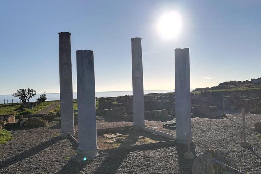 Ancient stone columns, a clear sky, and a distant coastline. 3