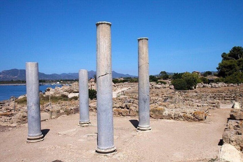 Ancient stone columns, a rocky landscape, and a body of water. 2