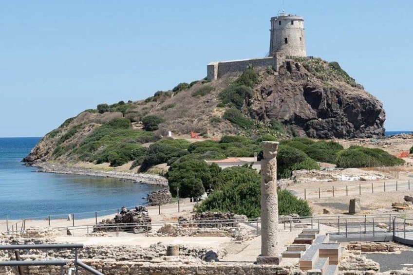 A coastal fortification with a tower, ruins, and a clear sky. 1
