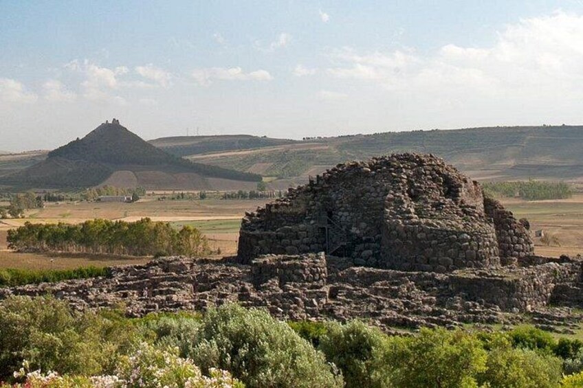 Ruinas antiguas en un paisaje rural con colinas ondulantes y una colina destacada al fondo. 1