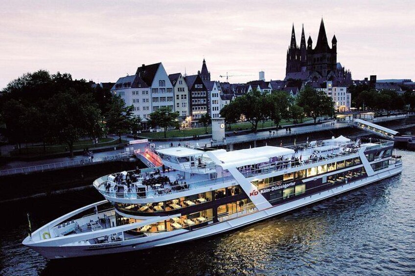 A river cruise ship with multiple decks, a cityscape with historic buildings in the background, and a castle-like structure. 2