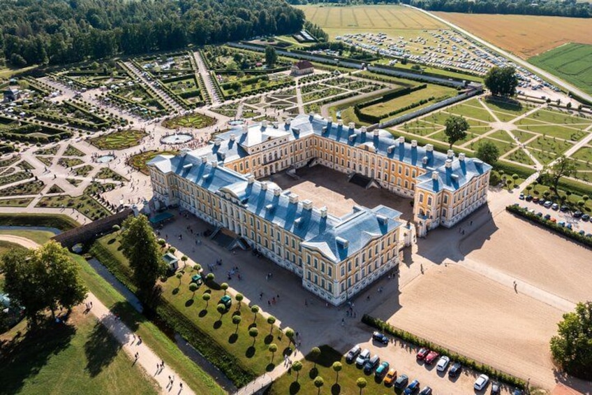 A large, ornate palace with a symmetrical layout, surrounded by manicured gardens and a formal park. 5