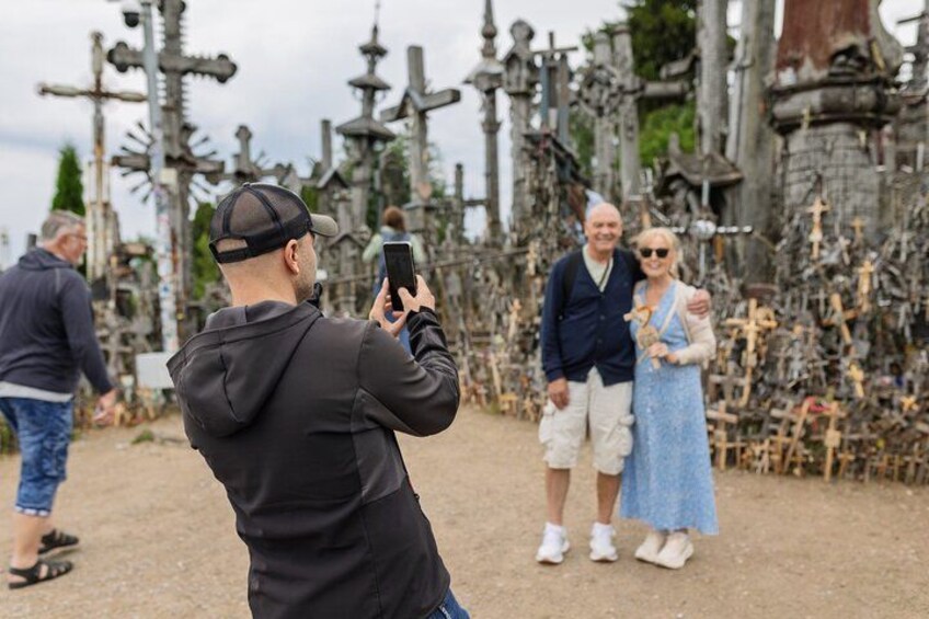A person taking a photo of a group of people standing in front of a structure with numerous crosses. 4