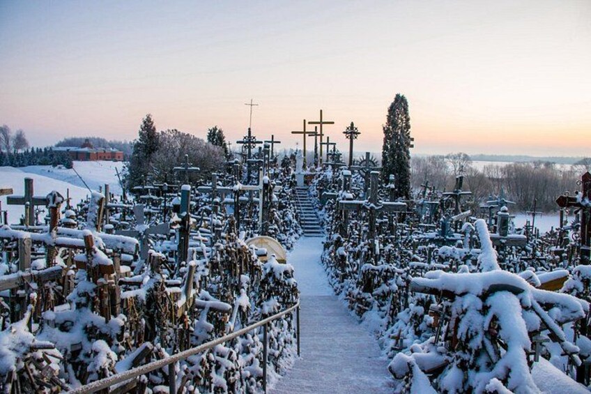 A cemetery with numerous crosses and gravestones covered in snow. 4